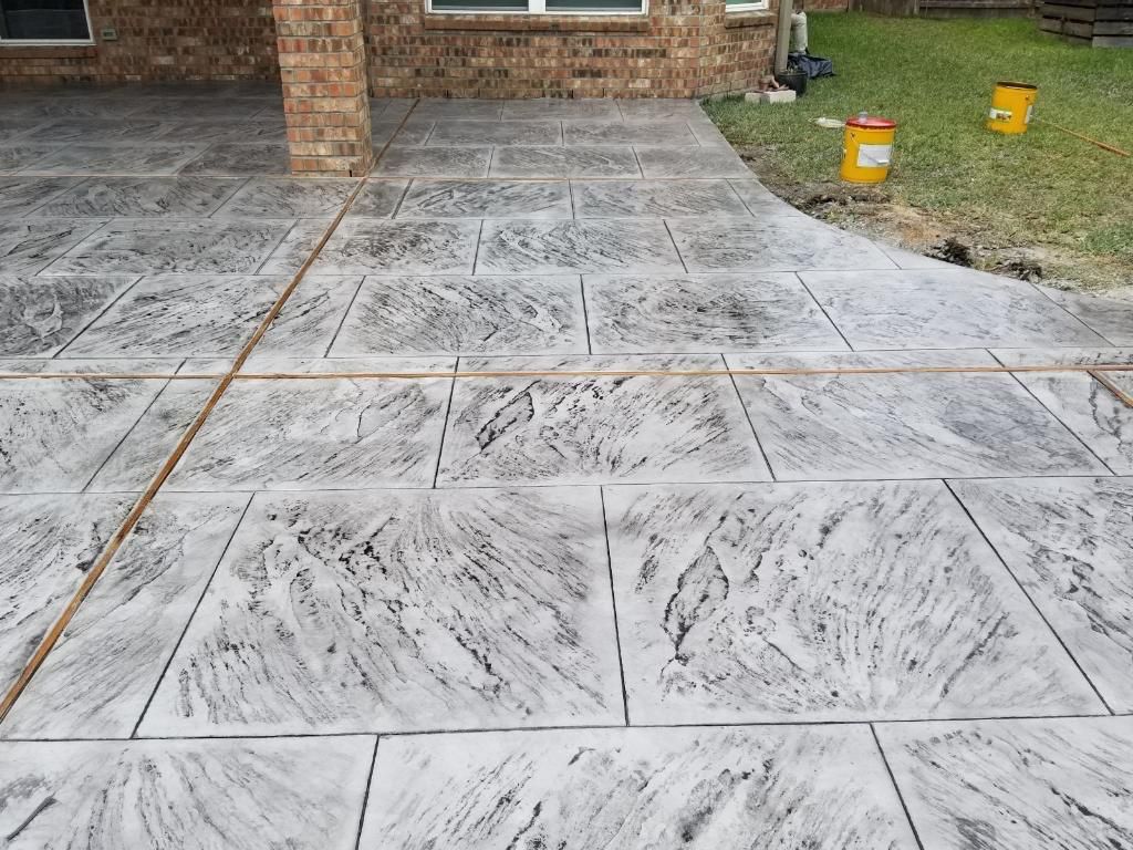 Major Transformation Project: Retaining Wall, Patio, and Drainage for Mr. & Mrs. Veerman! 🤩🛠️ We recently completed a comprehensive, custom project for Mr. & Mrs. Veerman that was all about structure, stability, and stunning outdoor design! This was a multi-phased project requiring the expertise of our Master Handcrafted Team.  Phase 1: Foundation and Water Management A successful outdoor space starts beneath the surface. We focused heavily on preparation and protection:  Demolition & Grading: We professionally removed and disposed of old dirt to achieve a level surface, ensuring the entire area was leveled and graded to enhance both appearance and functionality.  Comprehensive Drainage System: To prevent water issues and protect the new construction, we installed a complete system, connecting existing downspout gutters to channel drainage and strategically placed catch basins around the patio area.  Robust Concrete Foundation: Expert framing led to the pouring of a 4-inch deep, high PSI concrete slab to create a robust and lasting foundation for the entire retaining wall area.  Phase 2: Handcrafted Structure and Style This phase brought in our masonry and carpentry artisans to build the defining elements of the new space:  Custom Retaining Wall: Our master handcrafted team built a stunning, structural retaining wall. This involved careful framing, precise concrete work, and meticulous masonry construction with vertical supports every 3 feet for maximum stability.  Client Involvement: Mr. & Mrs. Veerman played a key role in selecting the retainer wall fascia and stone materials, ensuring the final look perfectly matched their vision.  Stamped Concrete Patio: We installed a beautiful stamped concrete patio. This decorative concrete work involved imprinting a pattern into the fresh concrete, giving them the high-end look of stone or brick with the durability of concrete.  Walk Add-On: Extended the stamped concrete to include a new, seamless walk area.  (Optional) Custom Garden Box: Constructed durable, raised garden boxes using 2"x12" boards and strong 4"x6" posts.  Phase 3: Landscaping and Finishing Touches The final details bring the entire project to life, focusing on irrigation and planting:  Sprinkler System Upgrade: To support their new landscaping, we upgraded their irrigation system by installing two new drip zones and a new control unit.  Flower Beds: Integrated new flower beds along the retaining wall and patio, ready for planting.  Decoration: Concluded the project with personalized decoration options to perfectly complement their beautiful, newly structured space.  Thinking About a Multi-Layered Outdoor Project? This project demonstrates our ability to seamlessly handle complex jobs—from heavy-duty drainage and structural construction to decorative finishes and irrigation.  The proposed timeline for this extensive project was 10 to 15 working days!  ❓ Do you have a sloping yard or drainage issues that could be solved with a functional and beautiful retaining wall? Tell us your challenge! 👇  💡 We specialize in bringing intricate outdoor visions to life! If you're looking for a team with master craftsmen for your next patio, retaining wall, or full landscape overhaul, let's talk. by Texas Urban Elements