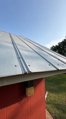 Completed metal roof on red building with clear sky