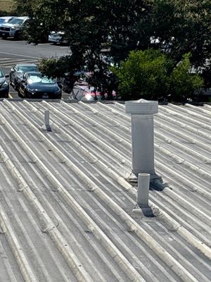 Corrugated metal roof with vents and parking lot view