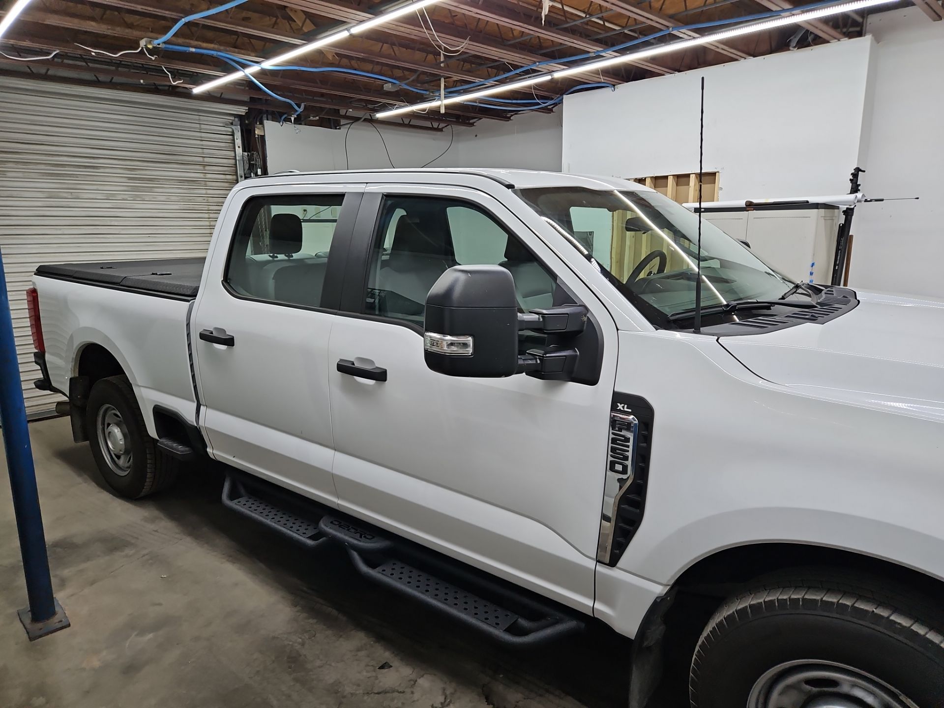 the service being done is window tinting on a white pickup truck the tint is applied to the windows to provide privacy and reduce glare the vehicle is likely in a garage or workshop setting the professionals are preparing the windows for a clean and precise installation this will enhance the vehicle's appearance and comfort while also offering protection from harmful uv rays