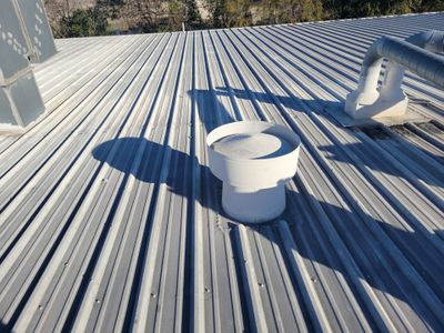 Metal roof surface with a circular ventilation cap installed.