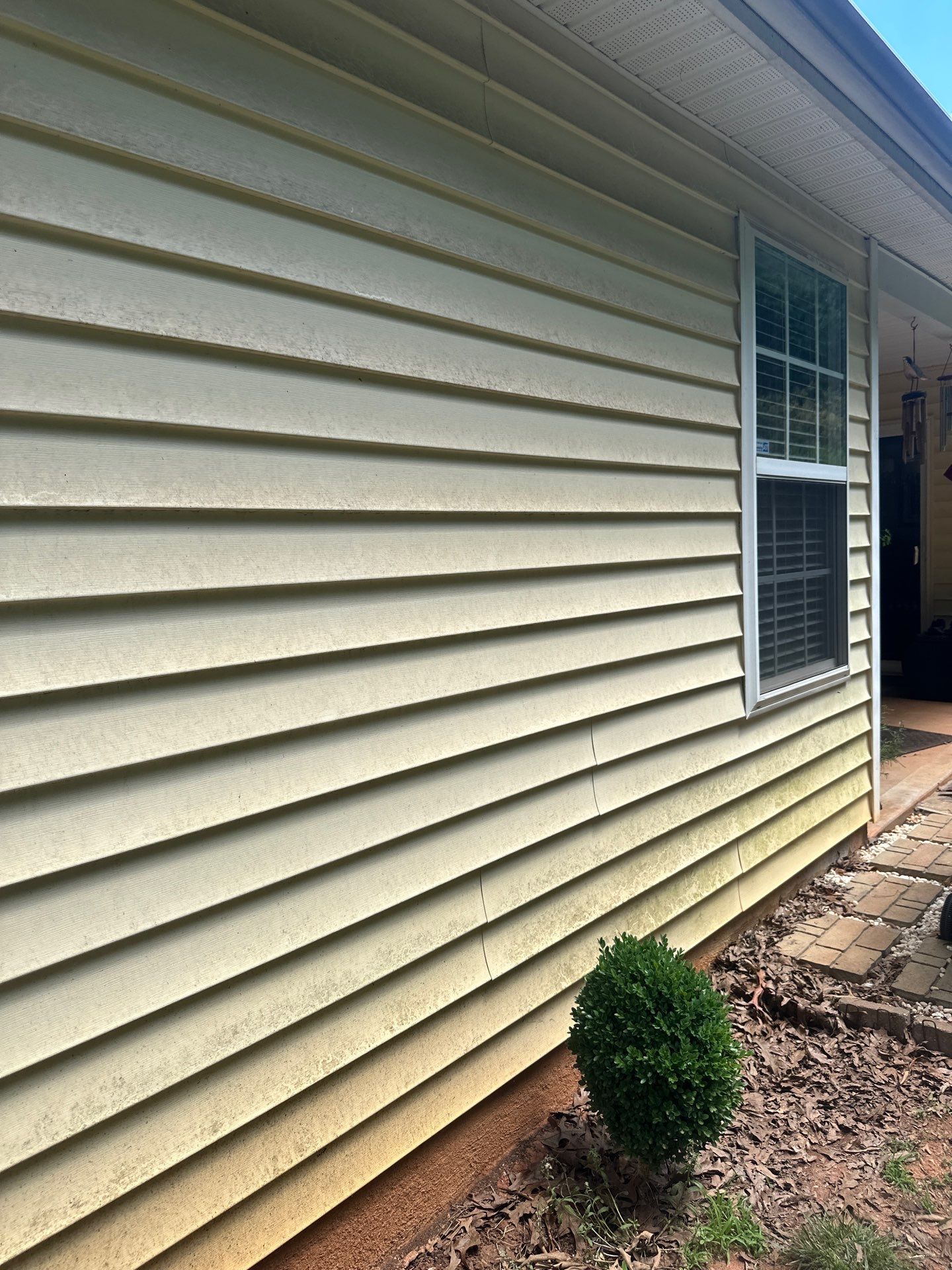 the photo shows the exterior walls of a house being cleaned by pressure washing the walls are made of vinyl siding which is a common material that can accumulate dirt mold and mildew over time the pressure washing process involves using high-pressure water to remove these substances restoring the siding to a cleaner and more visually appealing state the difference between the cleaned and uncleaned portions is clearly visible indicating the effectiveness of the service