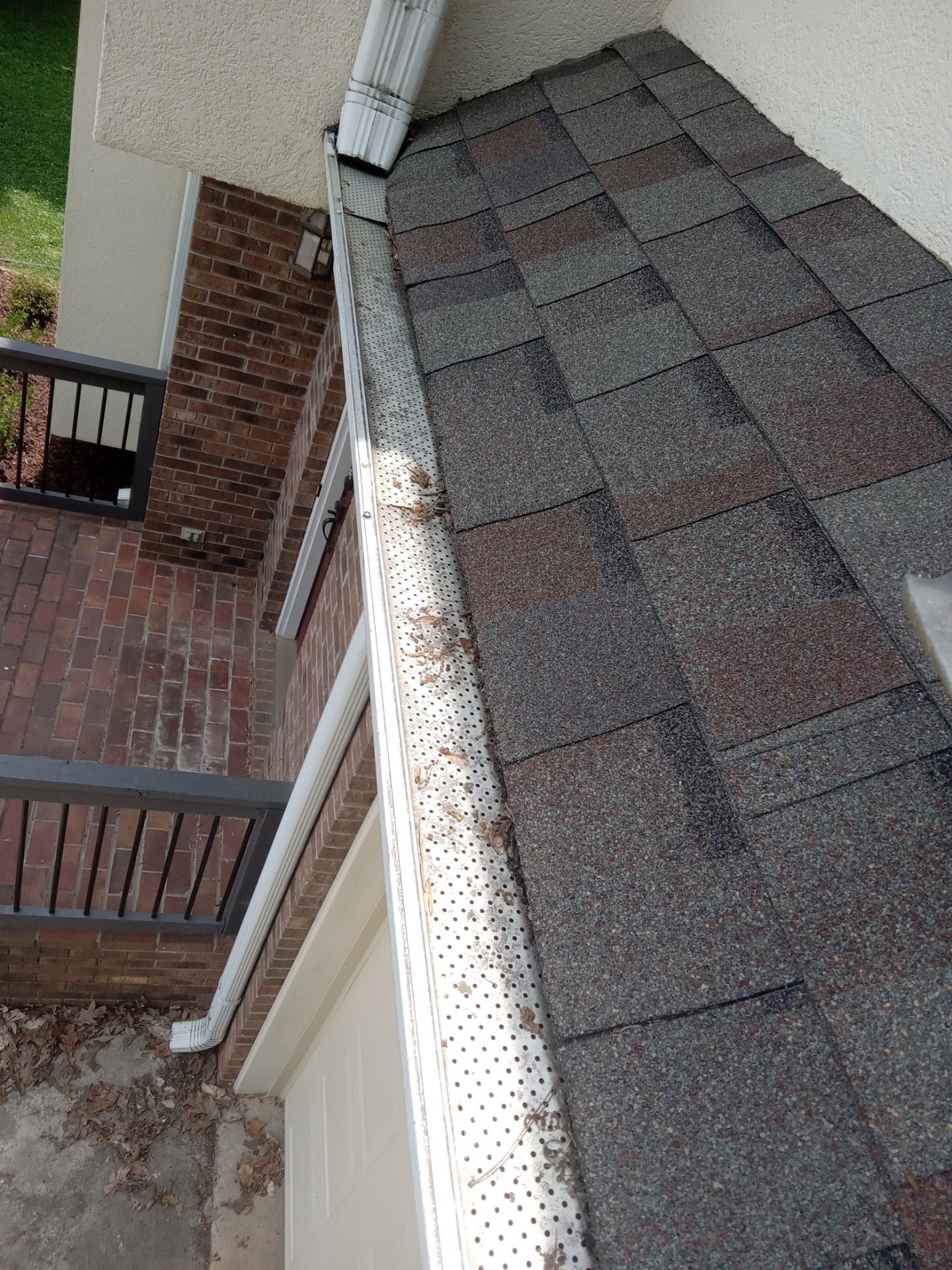 the pressure washing company based in kernersville nc is likely providing gutter cleaning services the photo shows a section of a roof with shingles and a gutter that is clogged with leaves and debris there is visible accumulation in the gutter indicating the service is needed for proper drainage and to prevent potential water damage or overflow the pressure washing service would involve removing the debris and flushing the gutters to ensure they are clear and functional