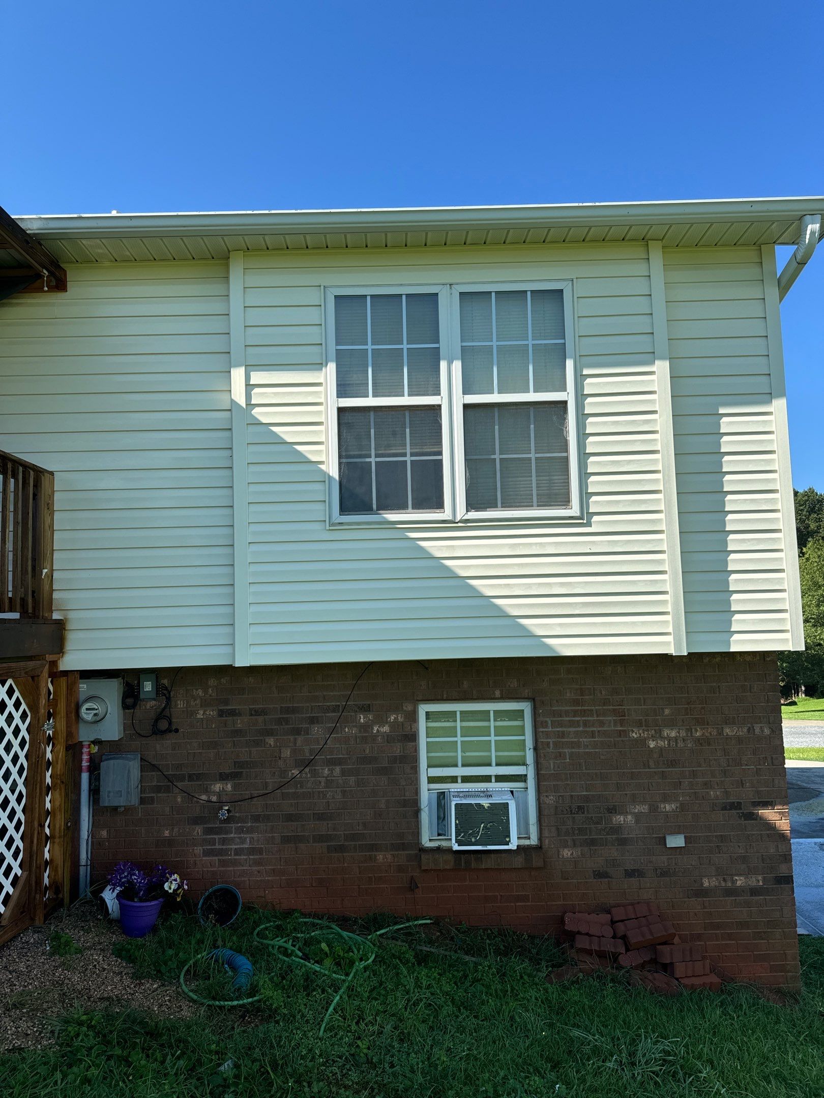 the surfaces being cleaned are the vinyl siding and brick foundation of the house to remove dirt and grime