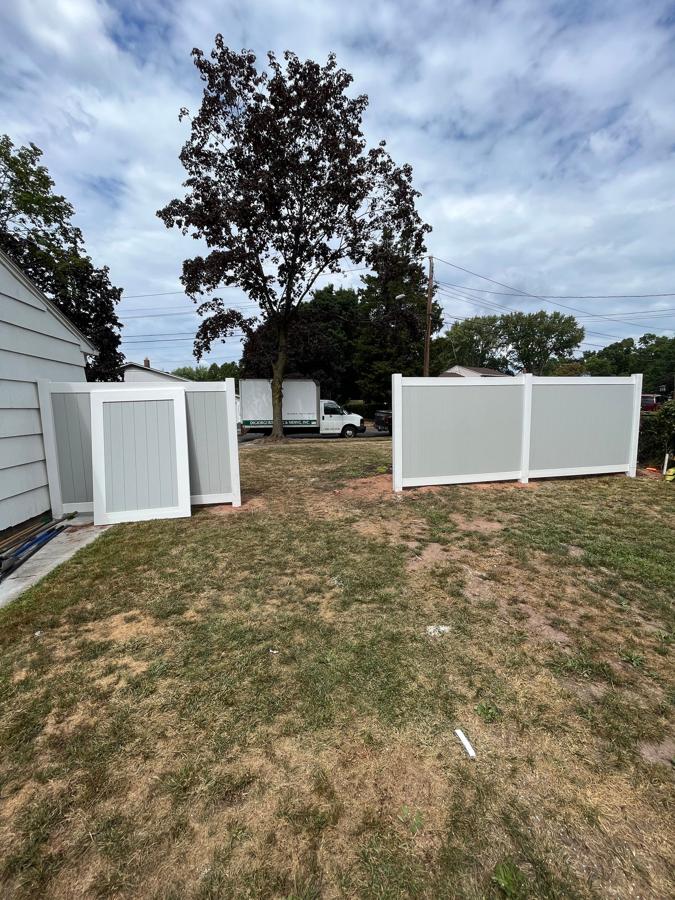 New Vinyl privacy fence with double gate. In two tone gray and white coloring. by DiGiorgi Roofing and Siding Inc