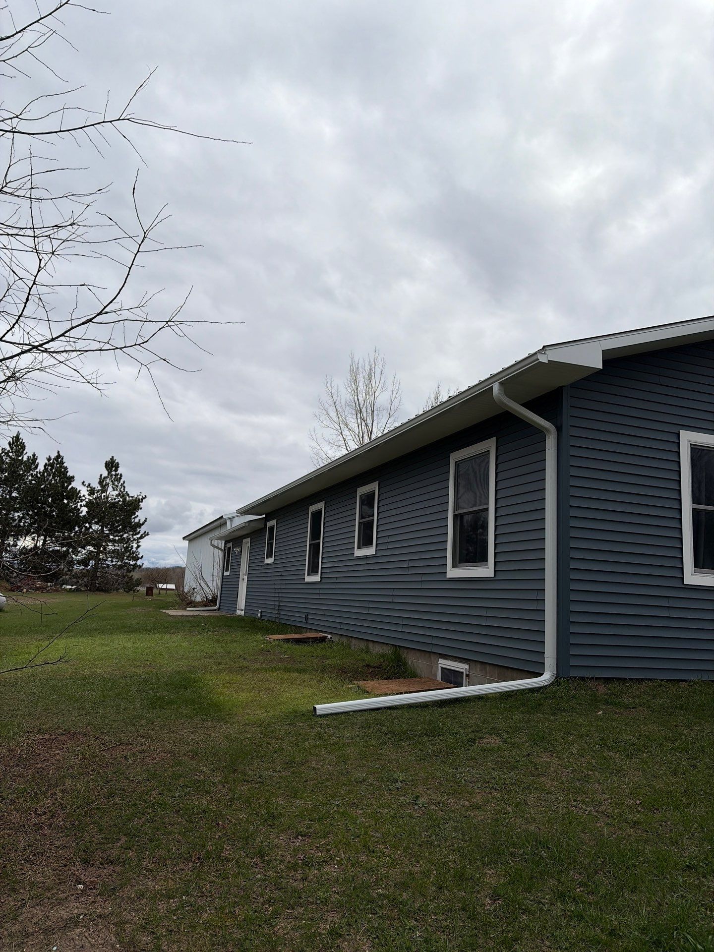 White Gutter and Downspout Installation for Boyne Falls Residential Property by Rainbow Seamless Systems