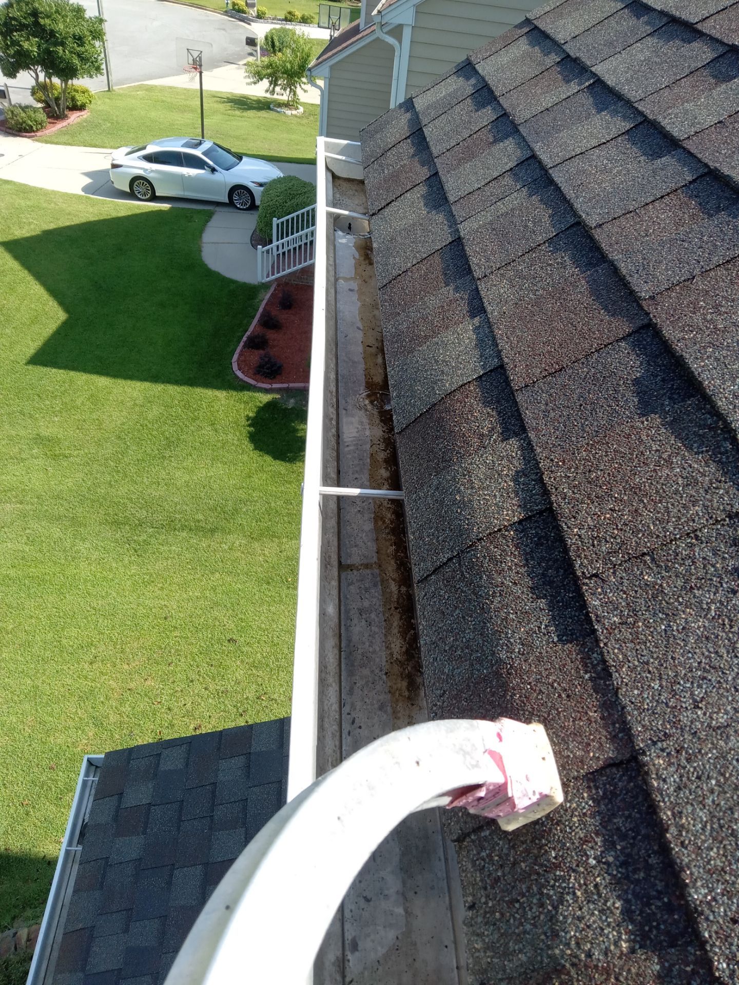 cleaning gutters removing debris and dirt from roof edges and gutter system with pressure washing equipment