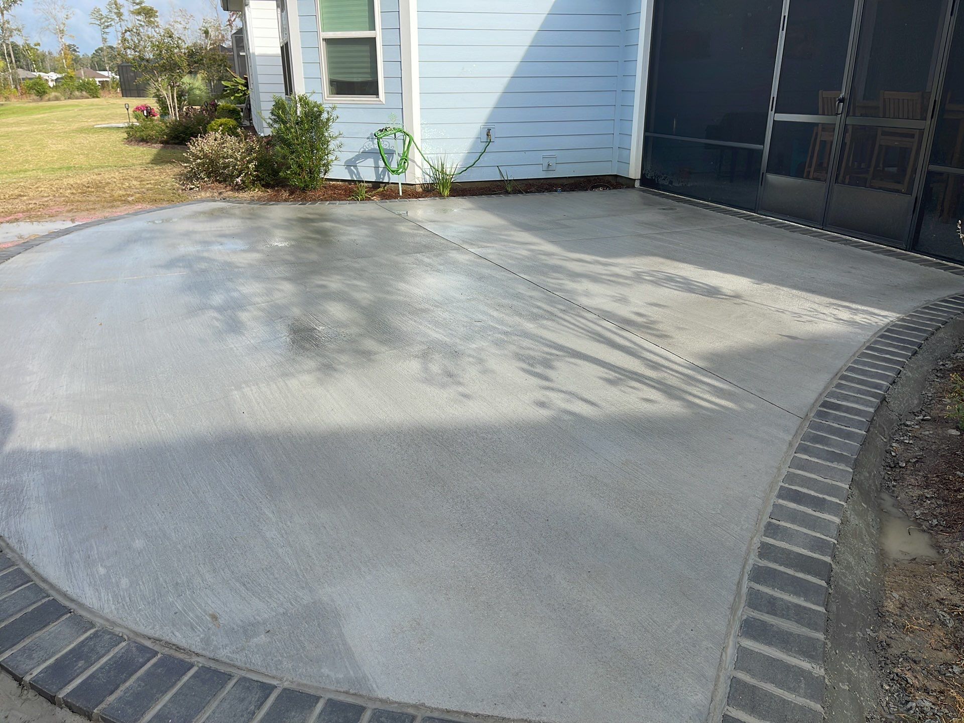 Custom Curved Concrete Patio and Paver Border in Hardeeville by Lowcountry Scapes, LLC
