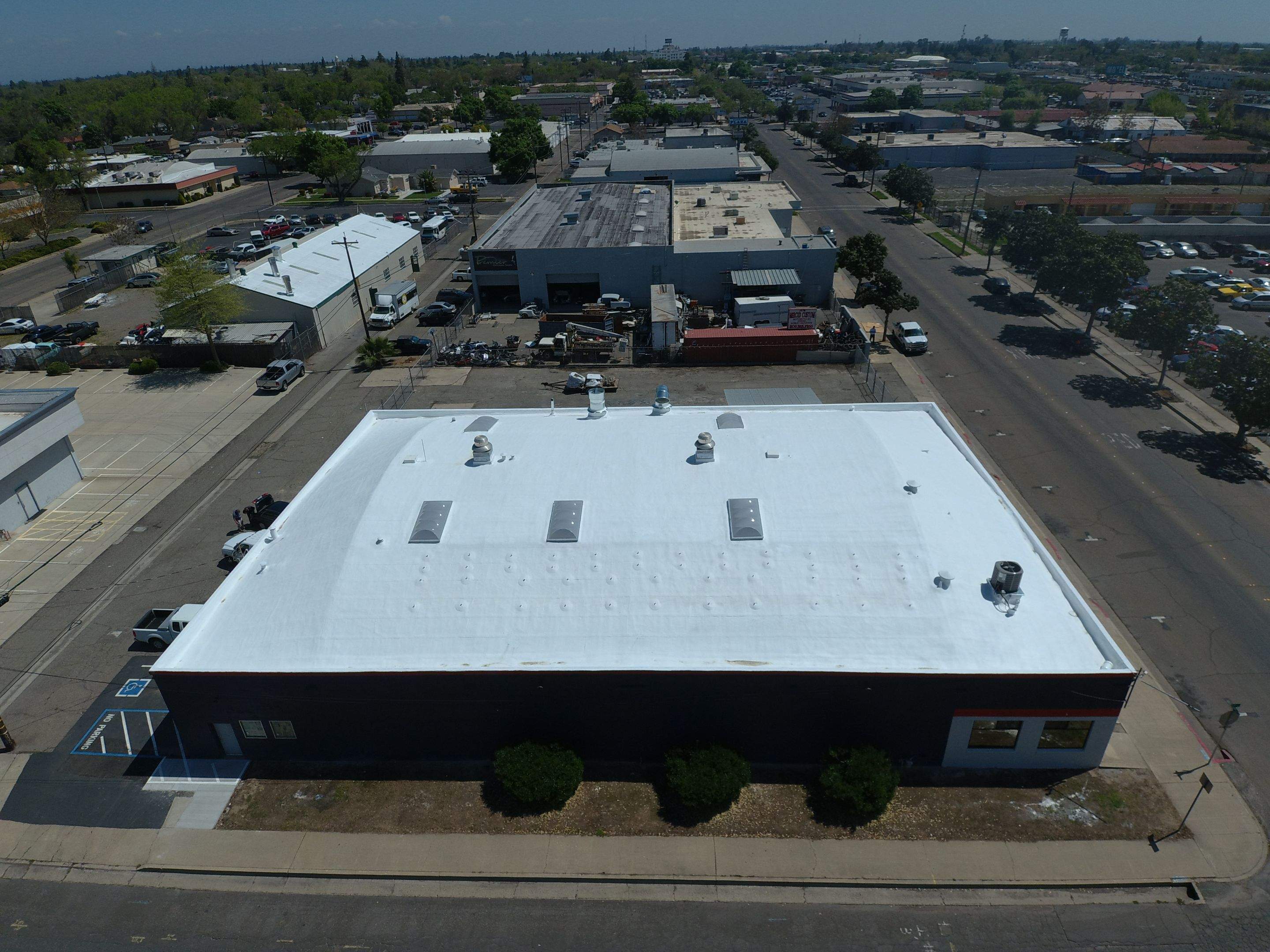 Spray foam and coatings using Conklin Benchmark/PUMA XL coatings on Auto Body Shop by Straight Edge Roofing Inc