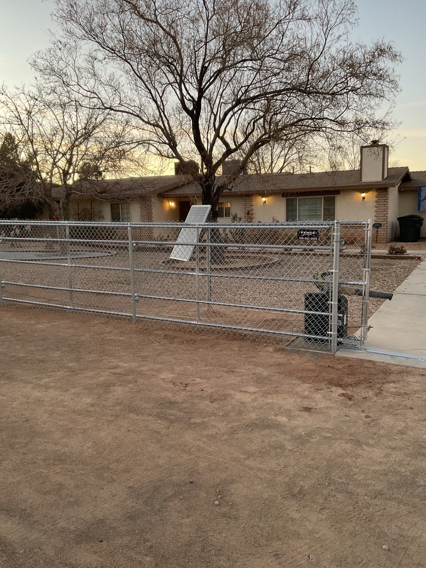 Sleek chain link fence installation with a solar motorized gate by Fence Guys Inc.