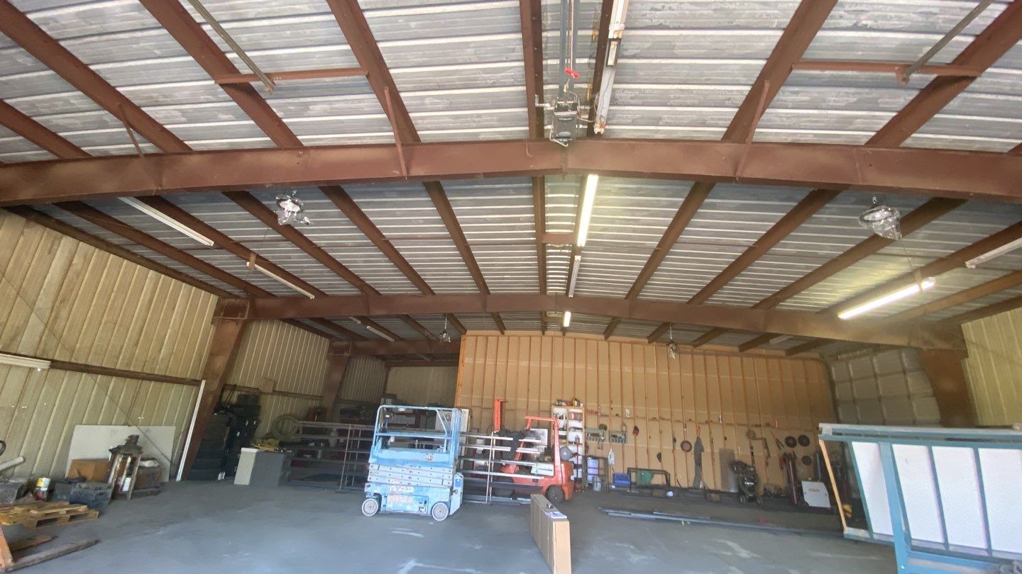 Spray foam insulation on inside of metal industrial building by Straight Edge Roofing Inc