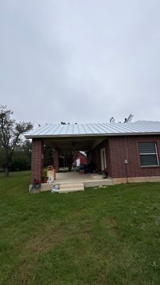 Completed metal roof on a red brick house exterior.