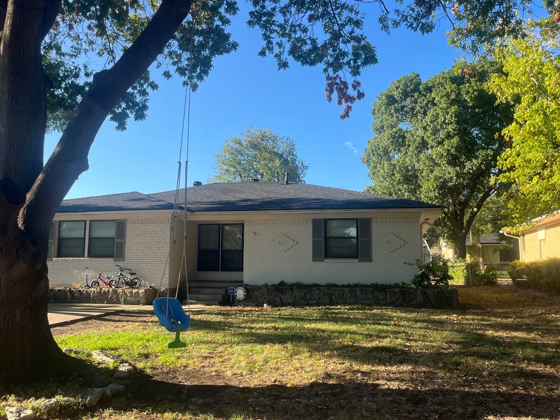 White brick/light gray shutters with IKO Granite Black  by Tejas Roofworks + Restoration