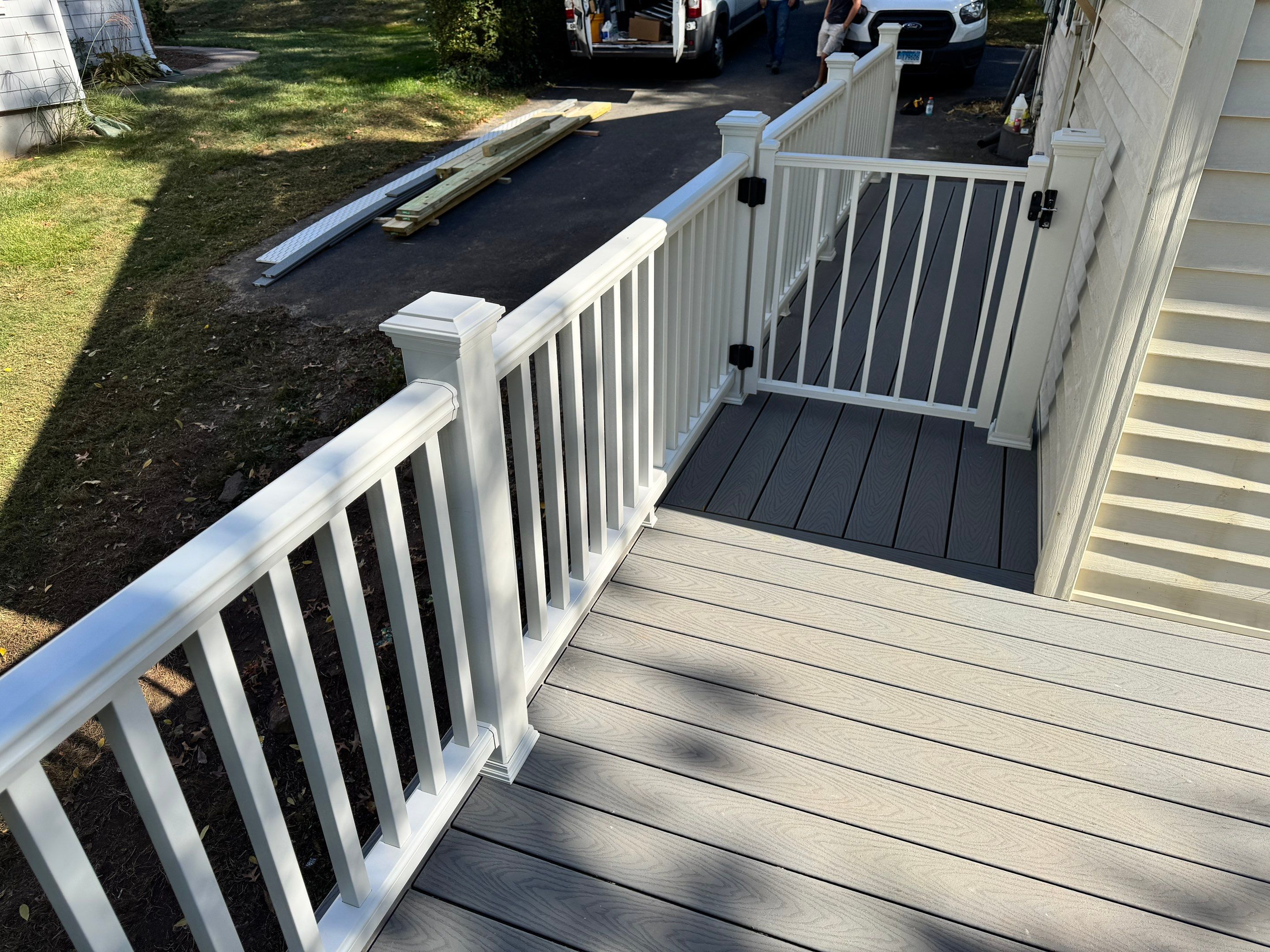 New Deck, Trex Select Pebble Gray boards, Composite railings in white, Trex Rainescape system, and gate. by DiGiorgi Roofing and Siding Inc