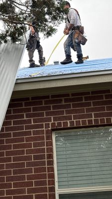 Workers installing standing seam metal roof panels.