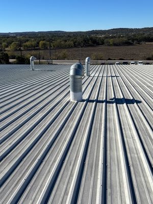 Wide view of metal roof with multiple vent pipes.