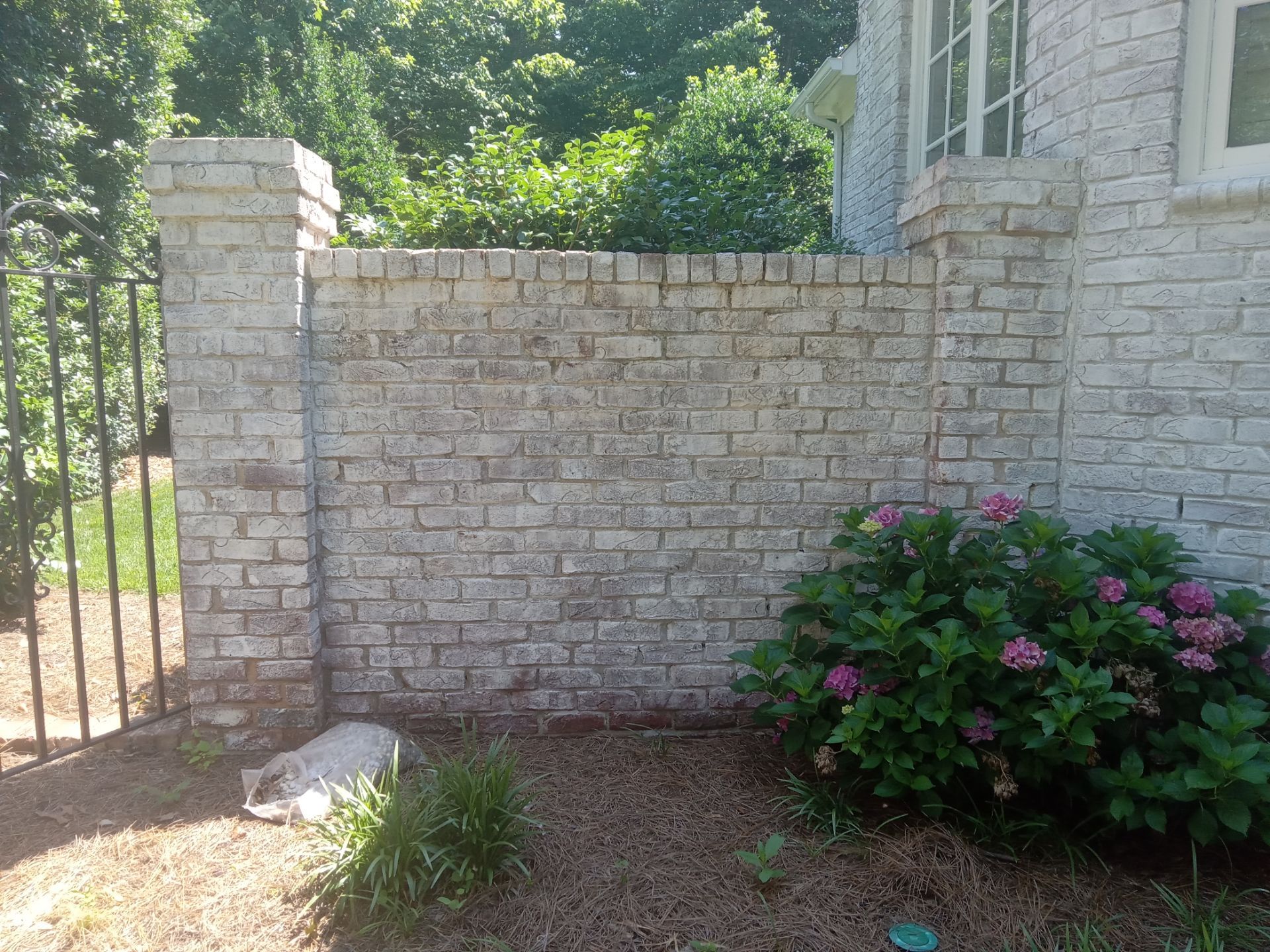 pressure washing stone wall and house exterior to remove dirt buildup and restore appearance