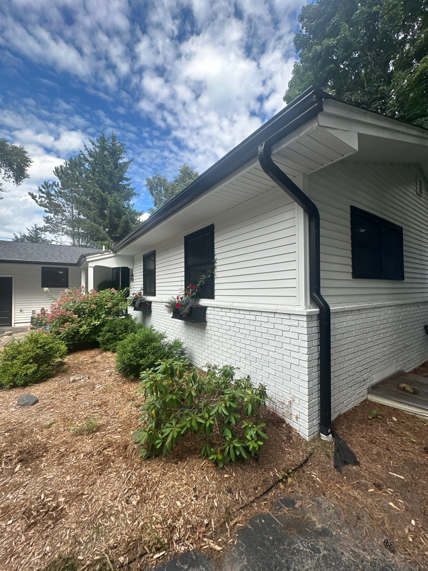 Black Gutter and Gutter Helmet Installation for Suttons Bay Home by Rainbow Seamless Systems