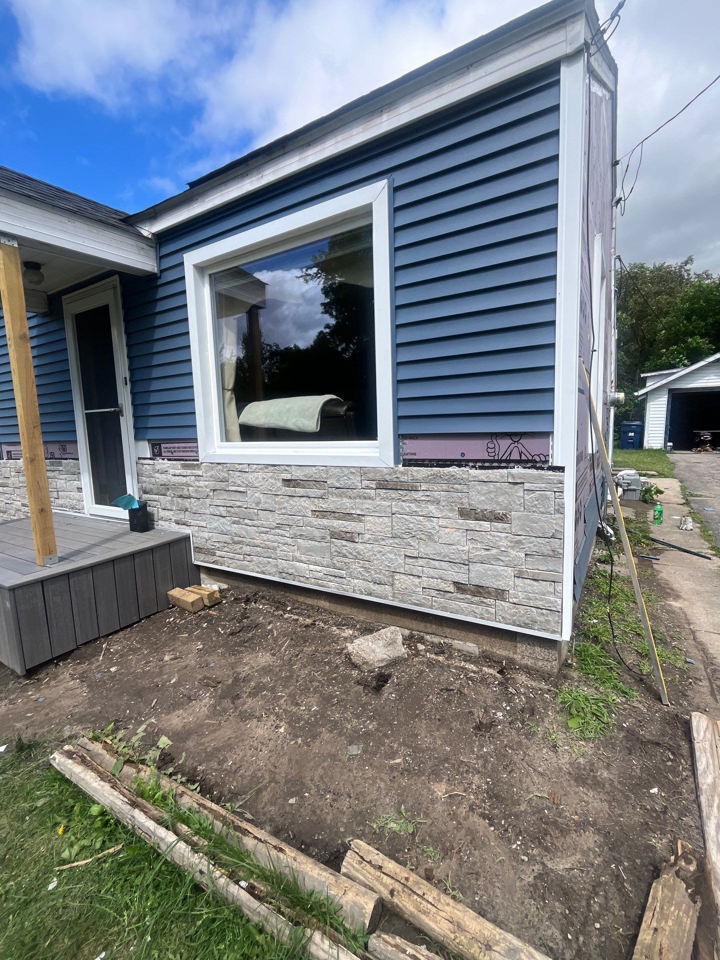 Blue Vinyl Siding and Versetta Stone Exterior Remodel in Bay City by Great Lakes Home Design LLC