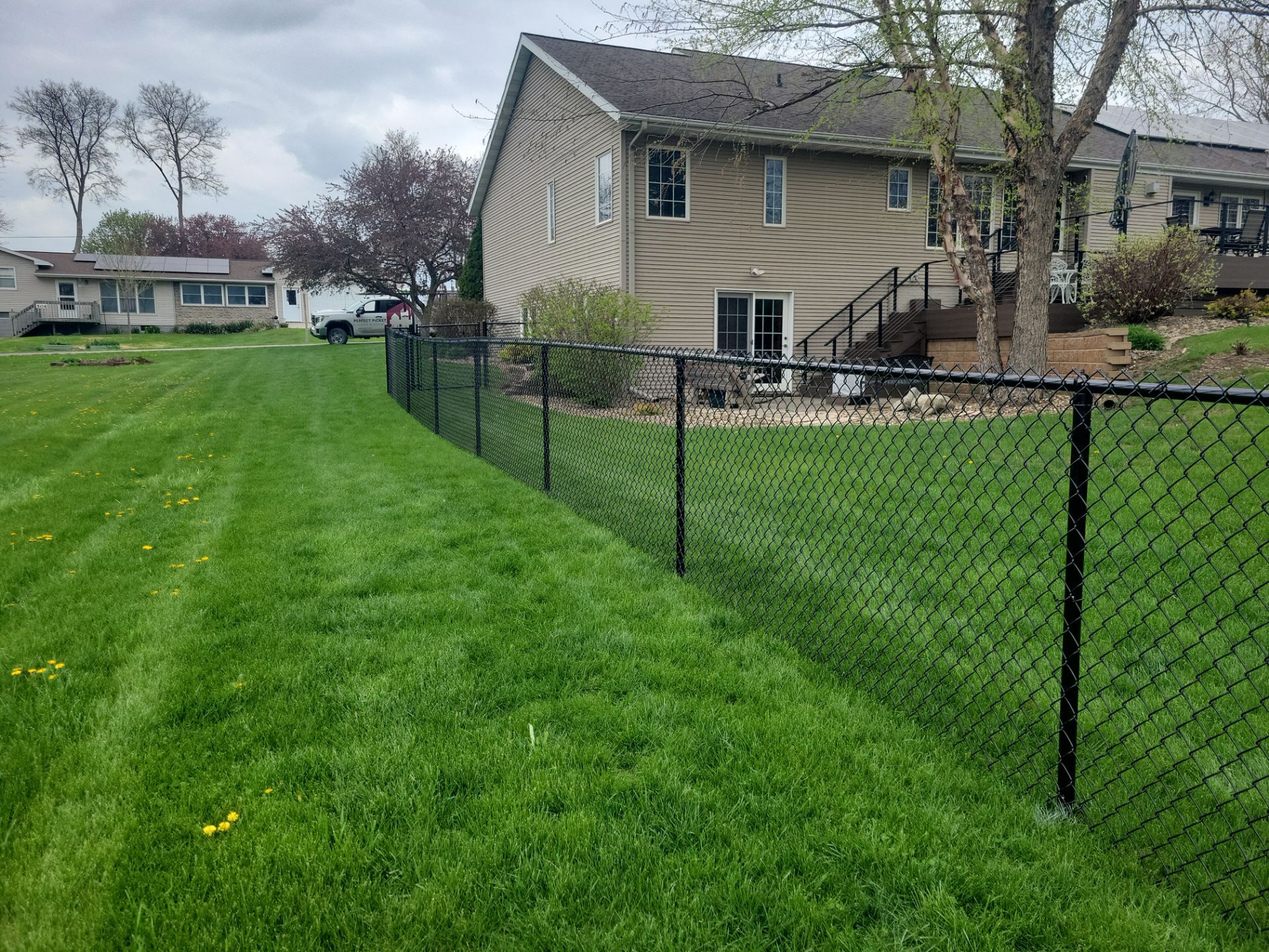 Residential Black Vinyl-Coated Chain Link Perimeter Fence in Garwin by Perfect Picket Fence and Stain
