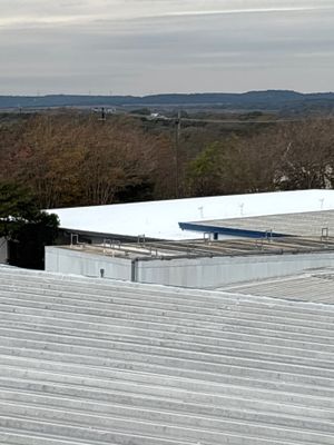 Wide view of industrial metal roof with surrounding landscape.