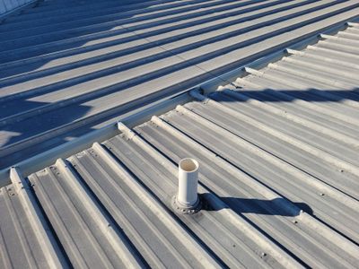 Metal roof surface with single pipe vent