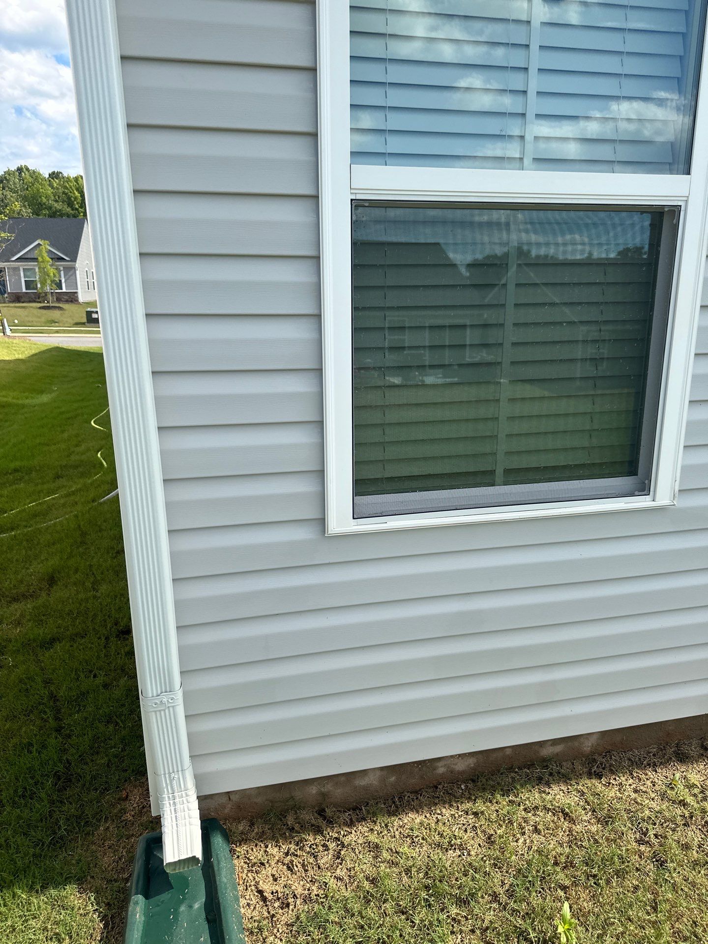 in this photo a pressure washing service is being provided to clean the exterior siding of a house in lancaster sc the siding appears to be vinyl and the pressure washing is likely intended to remove dirt grime and possibly mold or mildew that can accumulate on such surfaces over time the service also appears to be effective as the siding shows a noticeable difference between the cleaned area and the yet-to-be-cleaned area the downspout also seems to be part of the cleaning process ensuring all aspects of the home's exterior get attended to