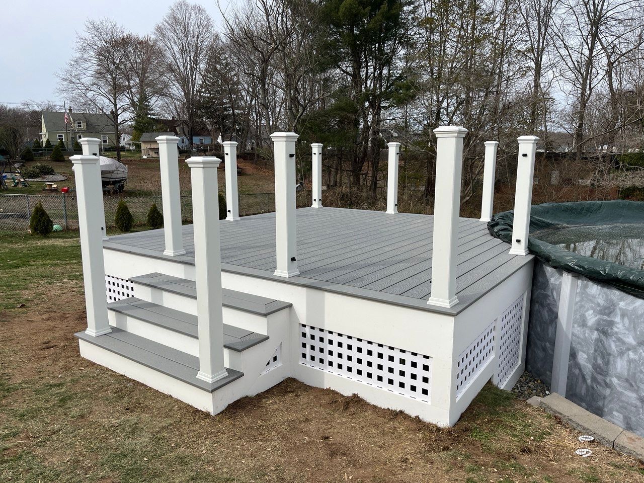 New pool deck using Trex Pebble Gray boards and White composite railings and lattice  by DiGiorgi Roofing and Siding Inc