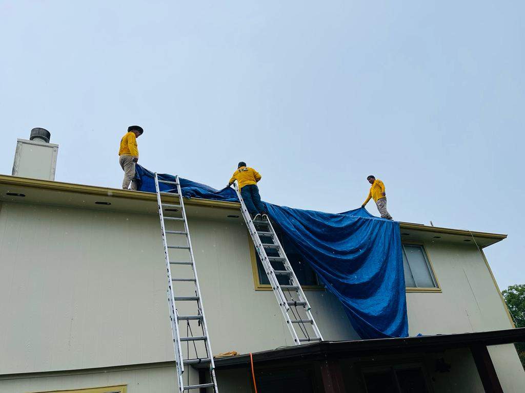 Placement of tarps on the roof. using TARP BLUE by V General Contractors 