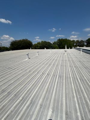 Wide view of completed corrugated metal roof with vents