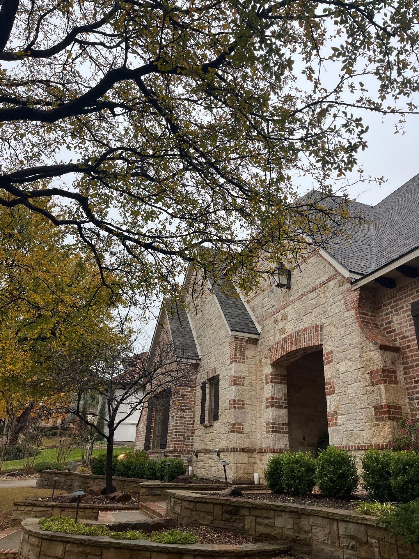Light red brick/cream stone/espresso shutters with IKO Cornerstone by Tejas Roofworks + Restoration