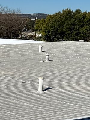 Metal roof with three vent pipes and trees