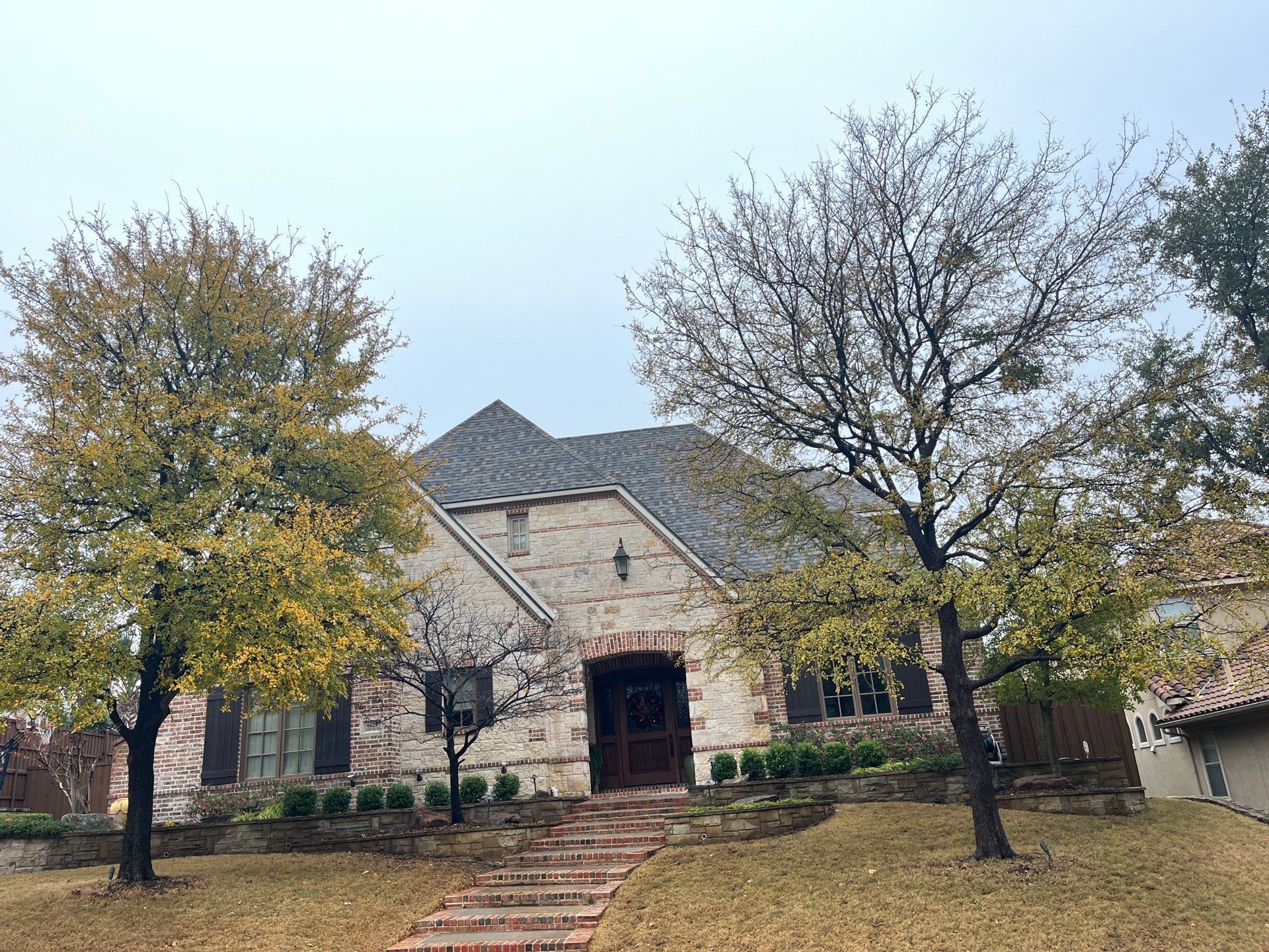 Light red brick/cream stone/espresso shutters with IKO Cornerstone by Tejas Roofworks + Restoration
