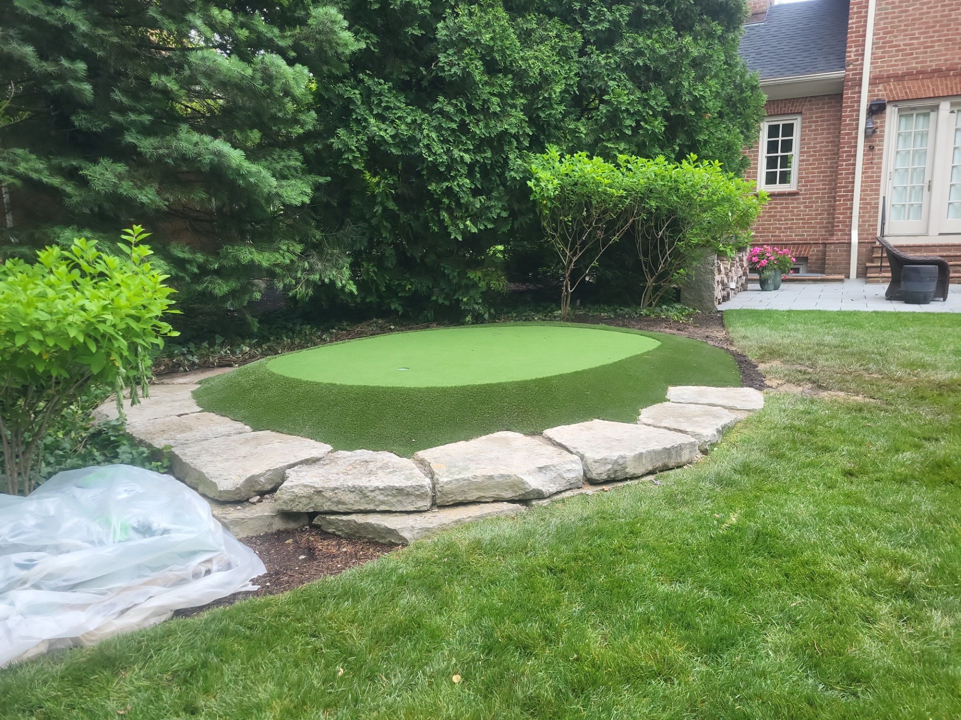 Small New Albany Synthetic Turf Putting Green with Natural Stone Border by Southwest Greens Midwest