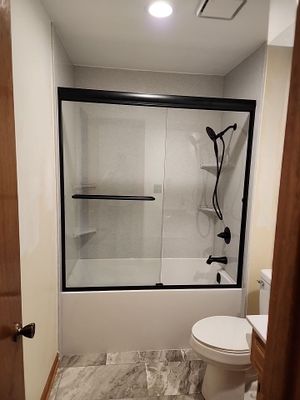 Bathtub, door, toilet, flooring, and countertop