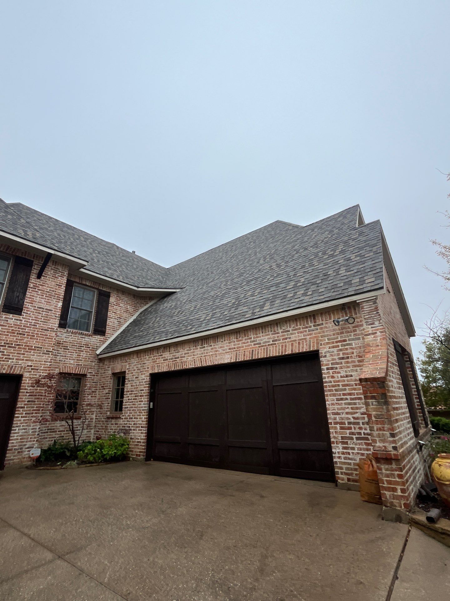 Light red brick/cream stone/espresso shutters with IKO Cornerstone by Tejas Roofworks + Restoration