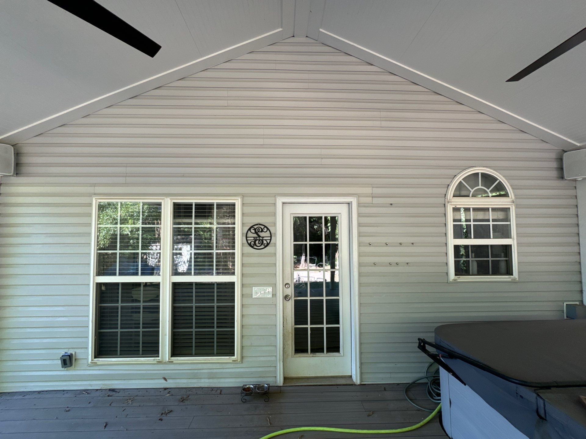 pressure washing company is cleaning vinyl siding windows and a patio deck