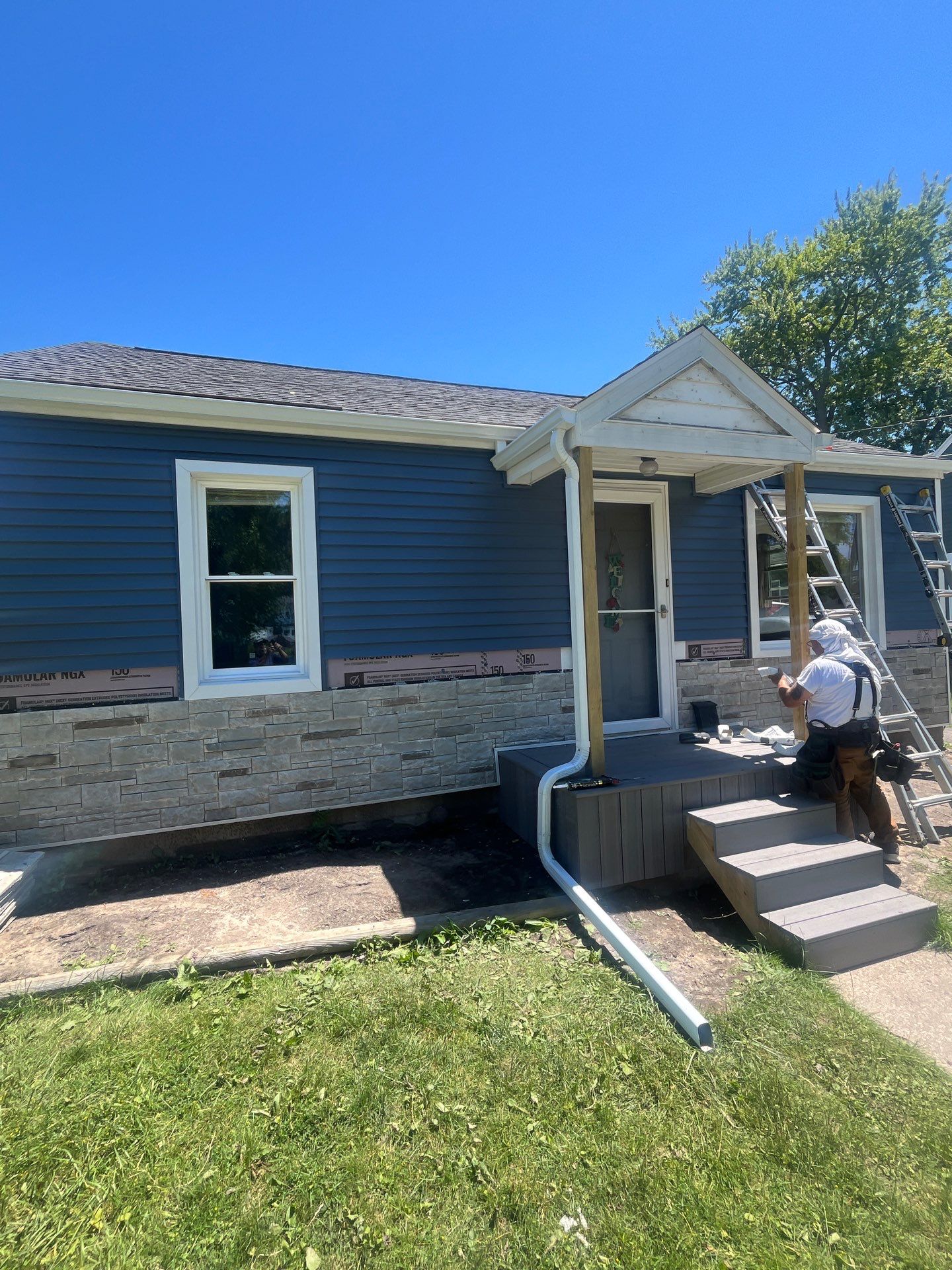 Blue Vinyl Siding and Versetta Stone Exterior Remodel in Bay City by Great Lakes Home Design LLC