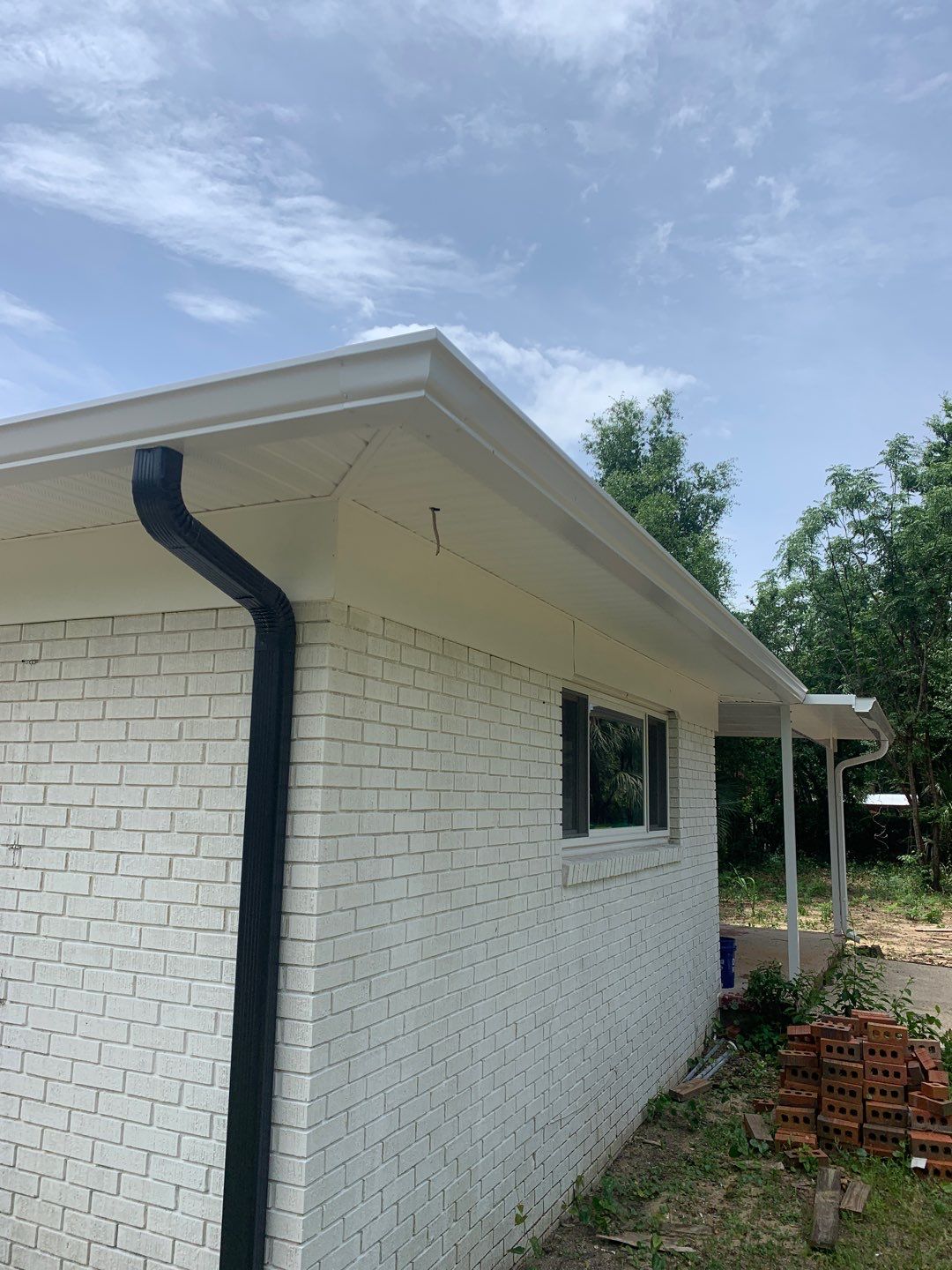 White Seamless Gutters and Black Downspouts by Gutter Professors