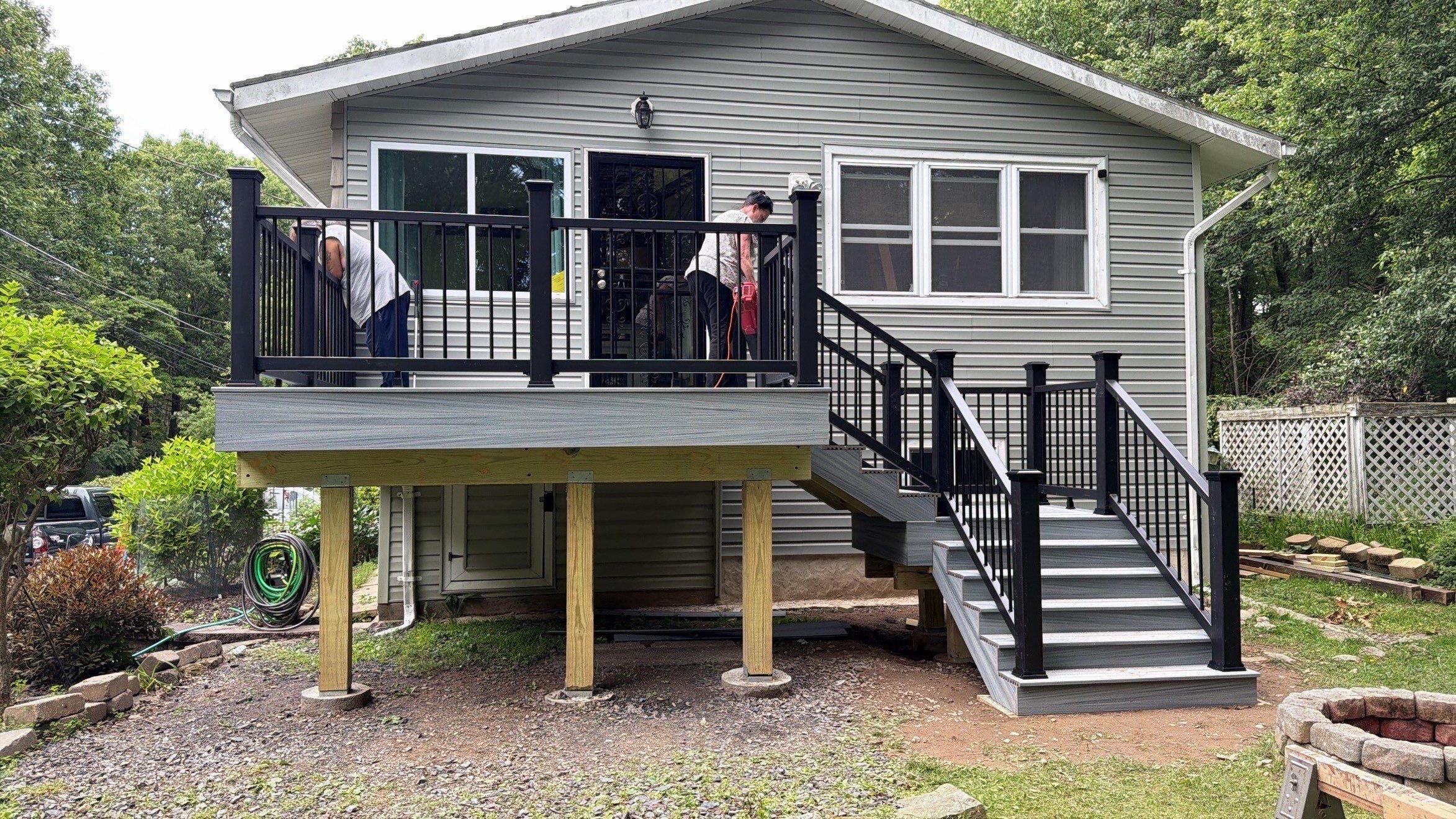 Raised Gray Composite Deck and Staircase Construction in Pocono Summit, PA by Herts Roofing & Construction