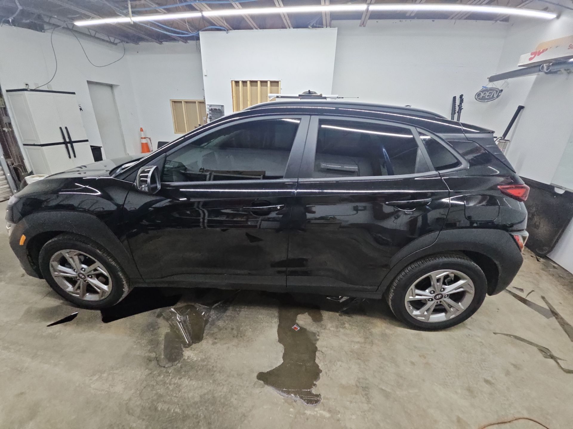 the service being done is window tinting on a black car which appears to be a compact suv the tint will enhance privacy reduce glare and help keep the car cooler in hot weather the work is likely being performed in a professional setting to ensure a clean application and high quality result the interior is likely being protected from any debris during the tinting process