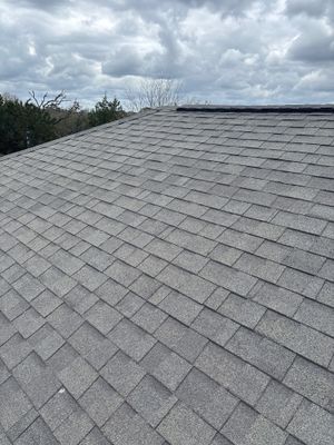 Architectural asphalt shingle roof under a cloudy sky.