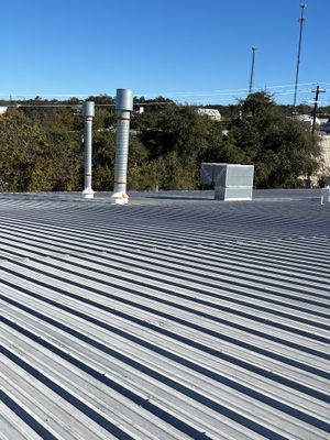 Metal roof with two vent pipes and HVAC unit