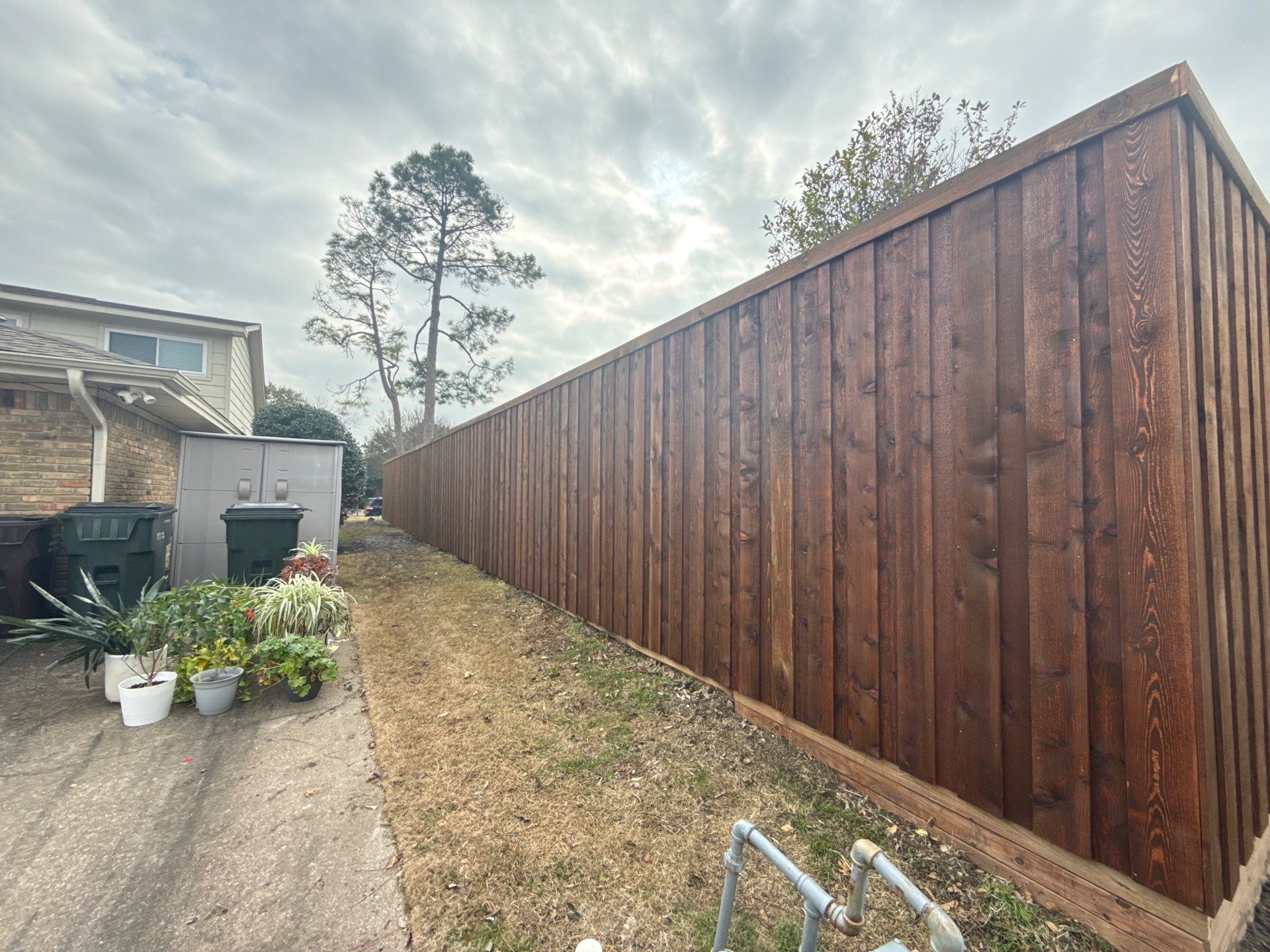 Pre-Stained board on board w/ trim and kickboard using 1x4 cedar trim by Grizzly Fence And Patio