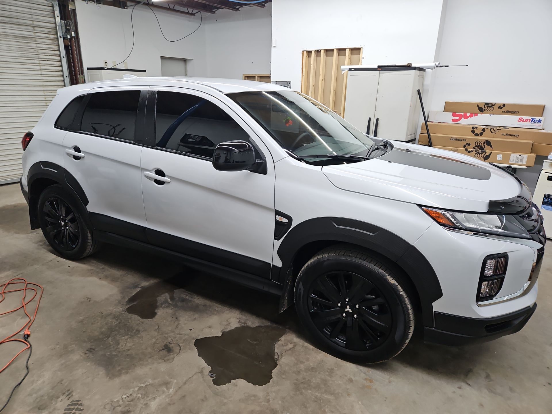 the service being done is window tinting on a white suv the windows have been tinted with a dark film providing privacy and reducing glare the job appears to be professionally done with clean lines around the edges the vehicle is likely in a garage or workshop indicating a controlled environment for the installation the darkened glass enhances the overall appearance of the car while also offering protection from uv rays and heat