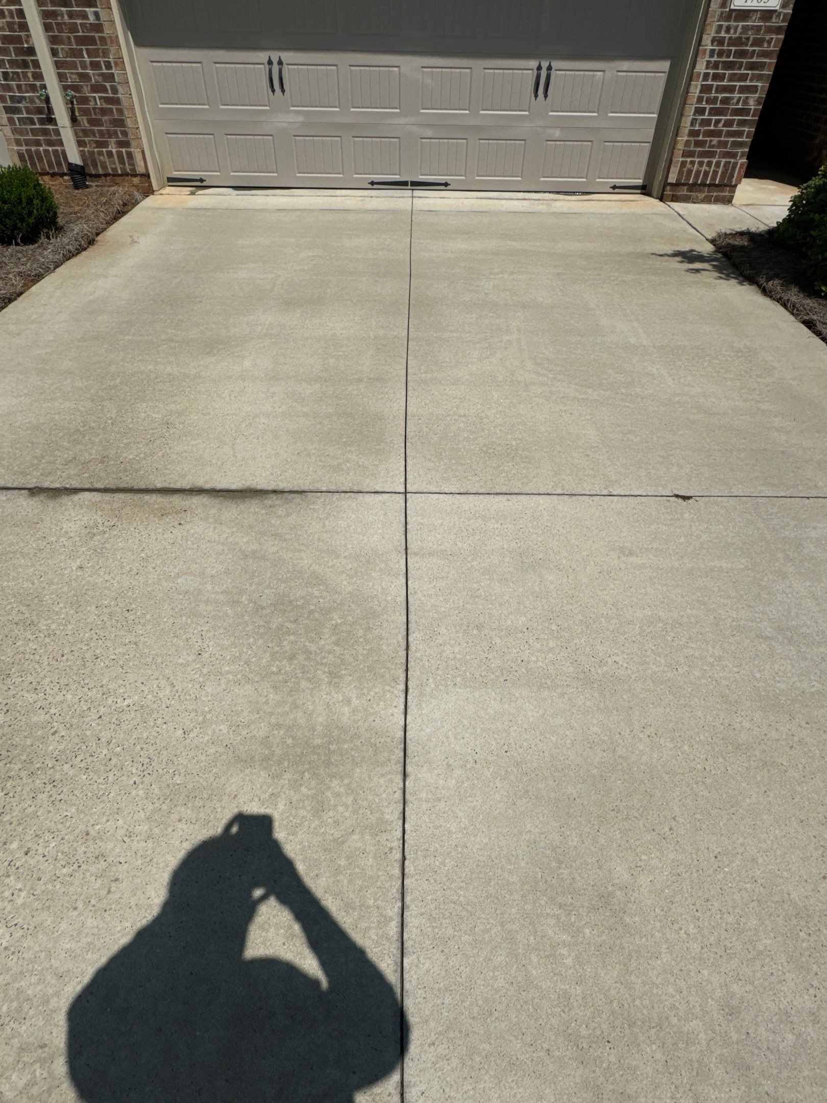 the photo shows a concrete driveway being cleaned with pressure washing removing dirt and grime for a fresh appearance