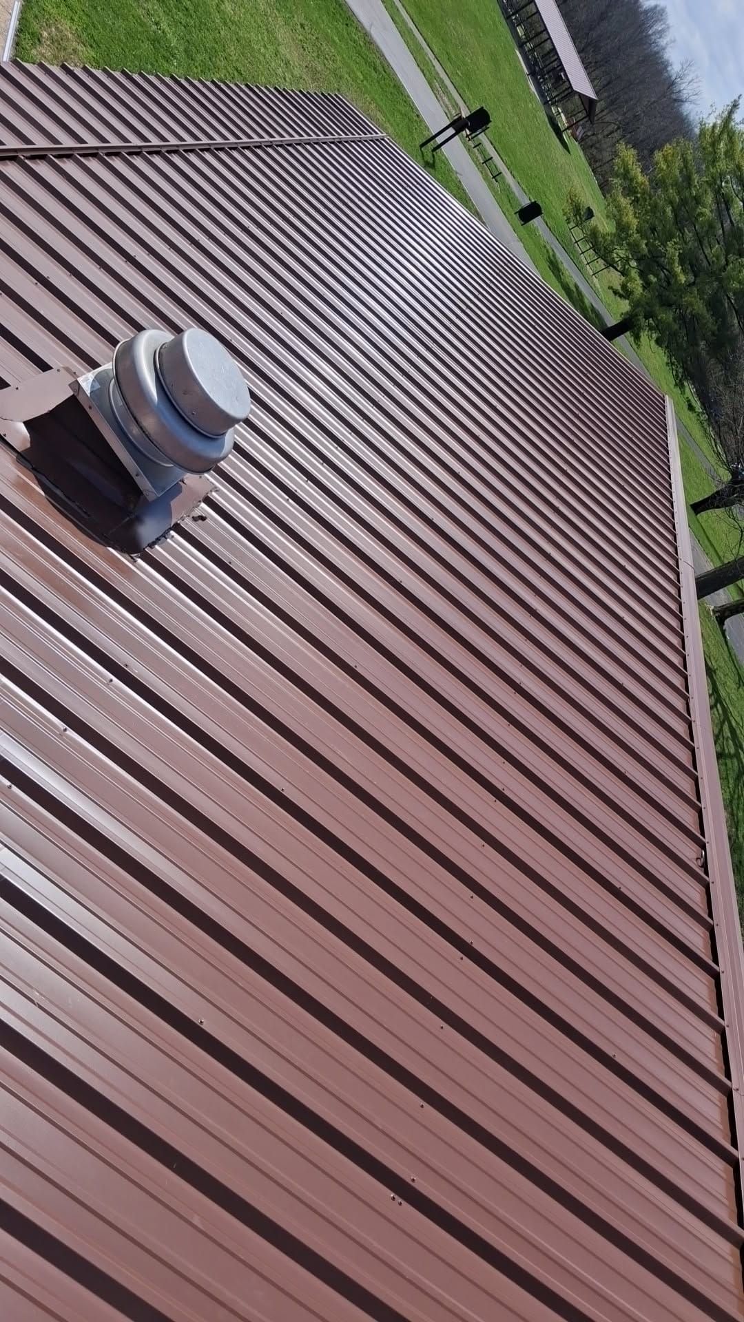 Brown R-Panel metal roof with solar by Atlas Roofing & Restoration
