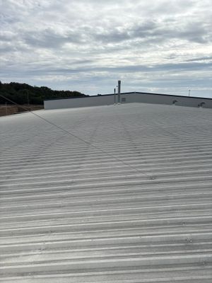Wide view of industrial metal roof with surrounding landscape.