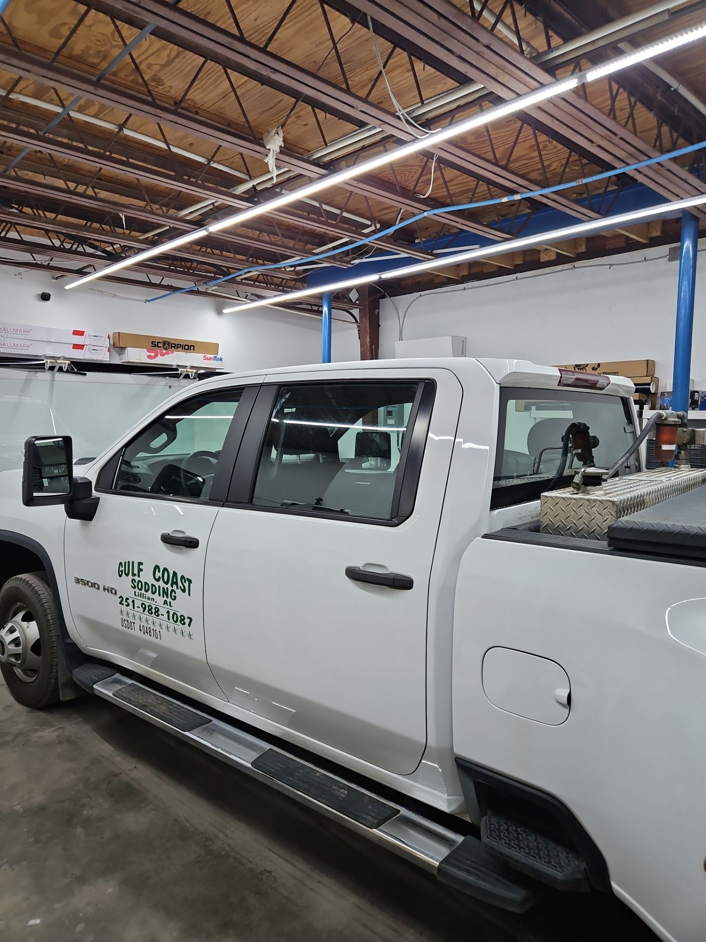 the service being done is window tinting on a white truck the tinting process involves applying a film to the windows to reduce glare and heat while providing privacy the truck is likely in a garage setting where the professionals can work without distractions this process enhances the vehicle's appearance and functionality