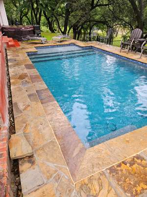 Geometric Pool with Raised Stone Wall and Flagstone Decking